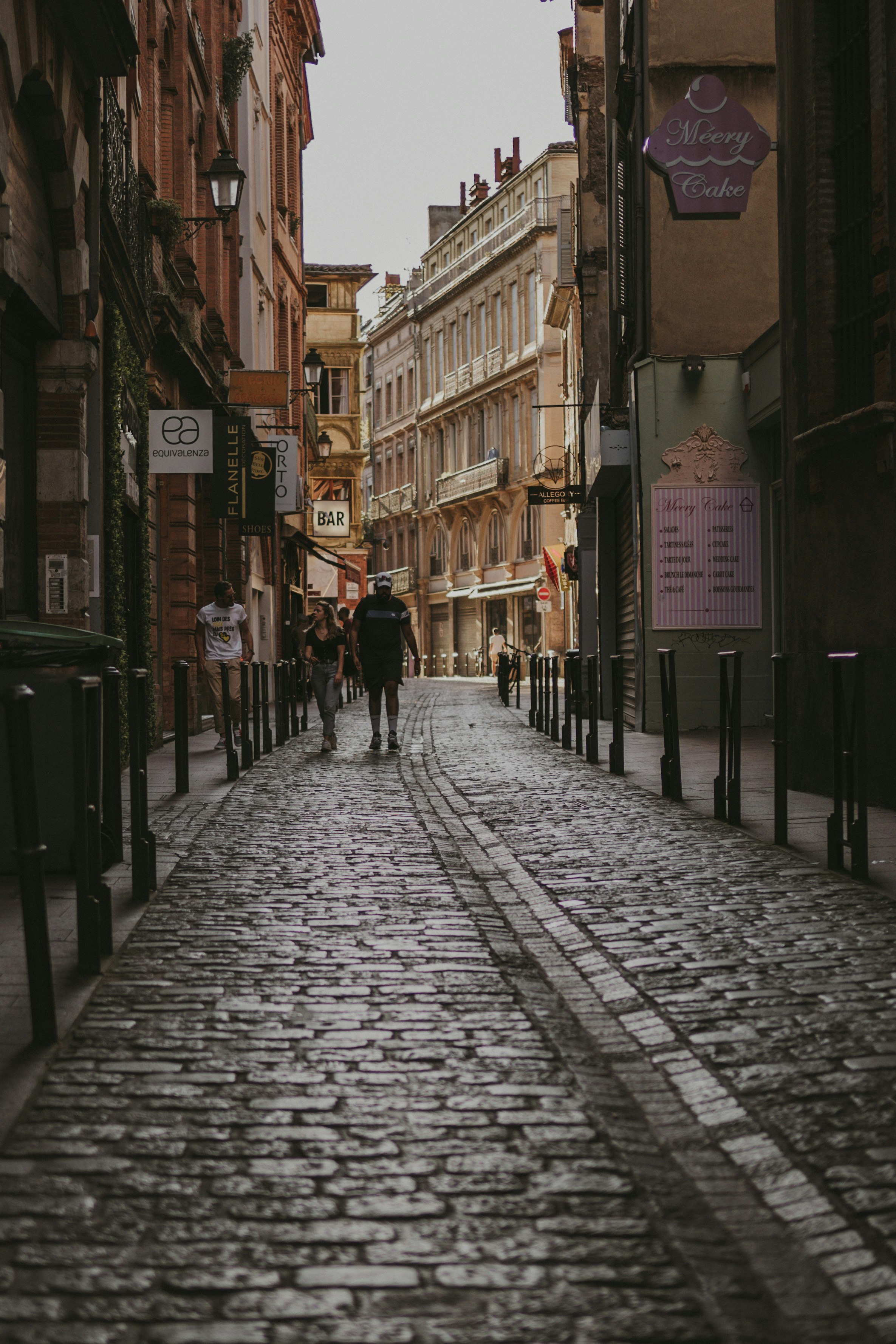 people walking on sidewalk between buildings during daytime